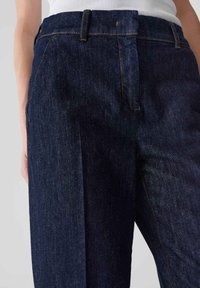Pantalons en denim bleu marine avec une coupe droite, présentant des coutures discrètes, des poches avant et une taille standard.