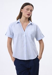 Camicia a maniche corte a righe blu e bianche con abbottonatura, colletto e taschino piccolo sul lato sinistro del petto. Tessuto di cotone liscio.