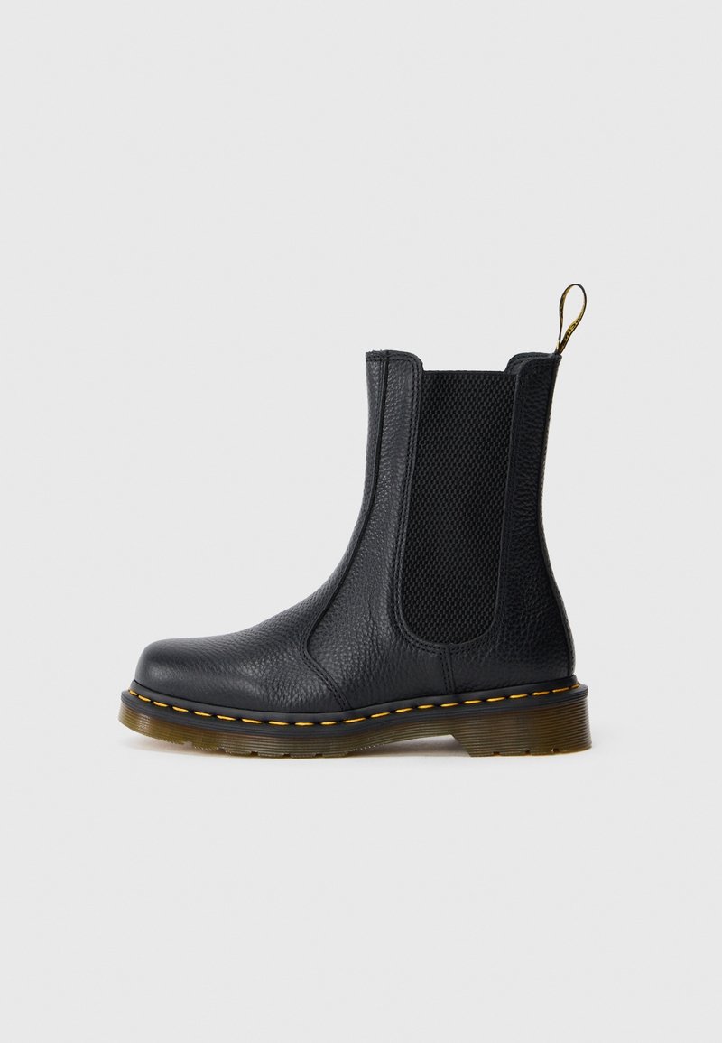 Botte Chelsea en cuir noir avec panneaux latéraux élastiques, surpiqûres jaunes sur la semelle et languette de tirage marron à l'arrière.