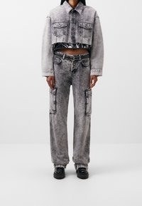 Lyhyet farkkutakki ja viittahousut haalistuneessa mustassa, jossa on teksturoidun näköinen pinta. Takissa on kaksi etutaskua; housuissa on sivutaskut.