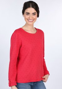 Rot gemusterter langärmeliger Pullover mit Rundhalsausschnitt und gestreiften Bündchen. Aus weichem Stoff gefertigt und mit einem floralen Design versehen.