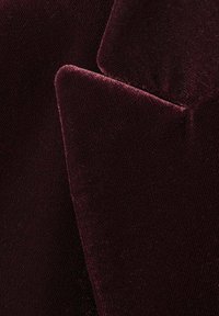 Cojines de terciopelo burdeos con una textura suave, que presentan esquinas marcadas y un acabado liso, creando una apariencia lujosa y rica.