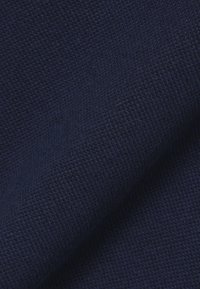 Nahaufnahme eines dunkelblauen, strukturierten Stoffes mit sichtbarem Strickmuster und Falten, die die Materialdetails und die Weichheit hervorheben.
