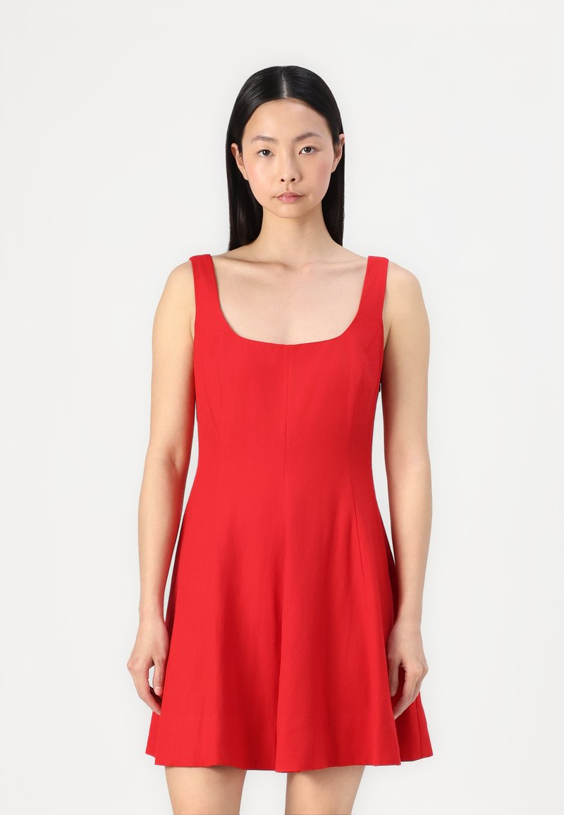 Robe rouge sans manches présentant un décolleté carré, un corsage ajusté et une jupe évasée. Fabriquée en tissu léger avec une texture lisse.