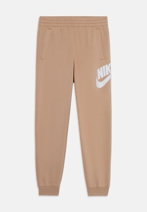 Beige Nike sporta bikses ar elastīgu jostu, divām sānu kabatām un lielu baltu logo uz kreisā augšstilba. Gluda tekstūra, sašaurināta piegriezuma.