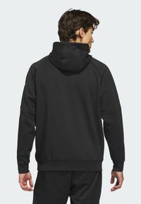 Black pullover hoodie made of soft fabric, featuring a spacious hood, raglan sleeves, and a relaxed fit, with no visible logos or patterns.