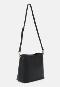 Sac à épaule en cuir noir avec une finition texturée, des accents en métal doré, une seule sangle réglable et un design à ouverture supérieure.