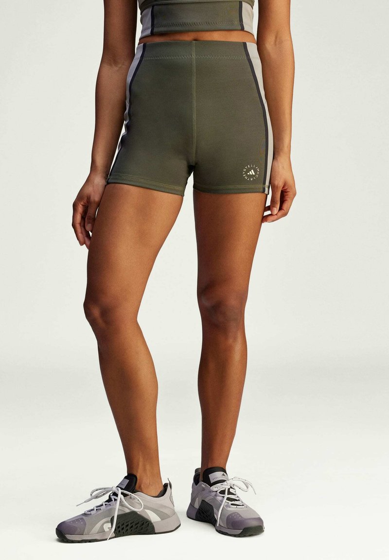 Shorts de sport taille haute, vert olive, avec des rayures sur les côtés, un design ajusté et un logo circulaire près de l'ourlet.