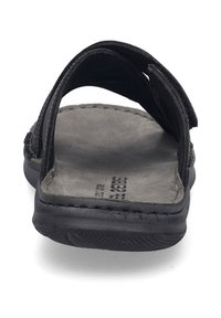 Sandales en cuir noir avec une semelle plate, des sangles supérieures ajustables et une semelle intérieure grise texturée. Les coutures sont visibles le long des bords.