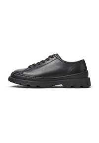Sneaker in pelle nera con profilo basso, caratterizzato da punta tonda, lacci e suola in gomma texturizzata per una migliore aderenza. Vista laterale su sfondo bianco.