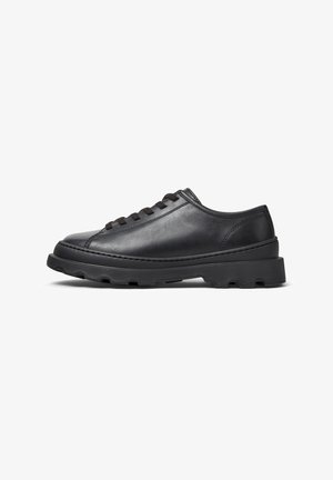 Czarne skórzane sneakersy o niskim profilu, z okrągłym noskiem, sznurków oraz teksturowaną gumową podeszwą dla lepszej przyczepności. Widok z boku na tle białym.