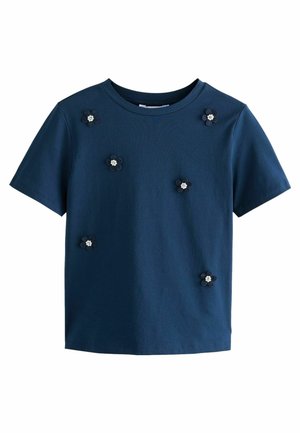 Chemise bleu foncé à manches courtes décorée de six petites fleurs foncées, chacune avec un centre blanc, espacées uniformément à l'avant.