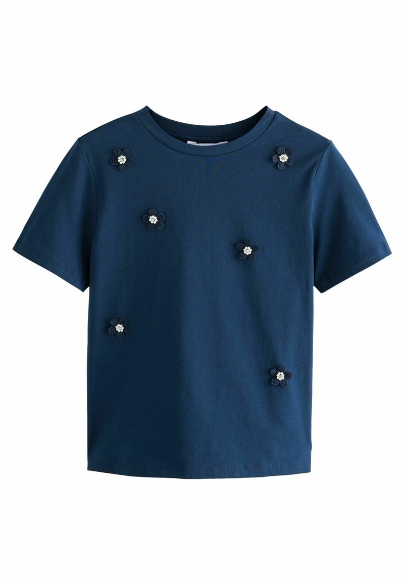 Chemise bleu foncé à manches courtes décorée de six petites fleurs foncées, chacune avec un centre blanc, espacées uniformément à l'avant.