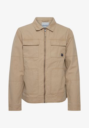 Beige, zippered jacket made of cotton with a collar, two chest pockets, and a logo patch on the left side. Features a relaxed fit.