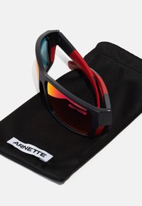 Sorte og røde solbriller med rektangulær fasong, speil-linser, matt rammefinish, og et beskyttende svart stoffetui merket "ARNETTE."