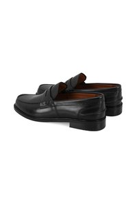 Zwarte leren loafers met gestikte accenten, ronde neus, elastische bovenkant, lage gestapelde hak en bruine leren voering.