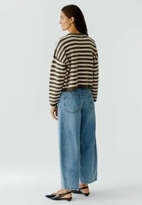 Gestreifter Pullover in Oliven- und Blushfarben, cropped Design; kombiniert mit hellblauen, weiten Jeans; schwarze Slingback-Schuhe; minimalistischer Stil.