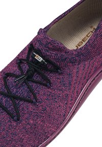 Fioletowe plecione trampki z czarnymi sznurówkami, teksturowaną górą i solidną podeszwą. Posiadają zamek do łatwej regulacji oraz wyściełane wnętrze.