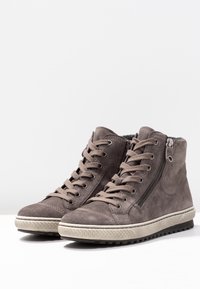 Pair of dark gray suede high-top sneakers with laces and side zippers, white textured soles on a white surface.