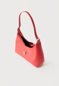 Κόκκινη δερμάτινη τσάντα ώμου με ασημένιο φερμουάρ που ανοίγει μερικώς, ρυθμιζόμενο λουρί και ασημένιο λογότυπο "SM" στο μπροστινό μέρος, σε λευκό φόντο.