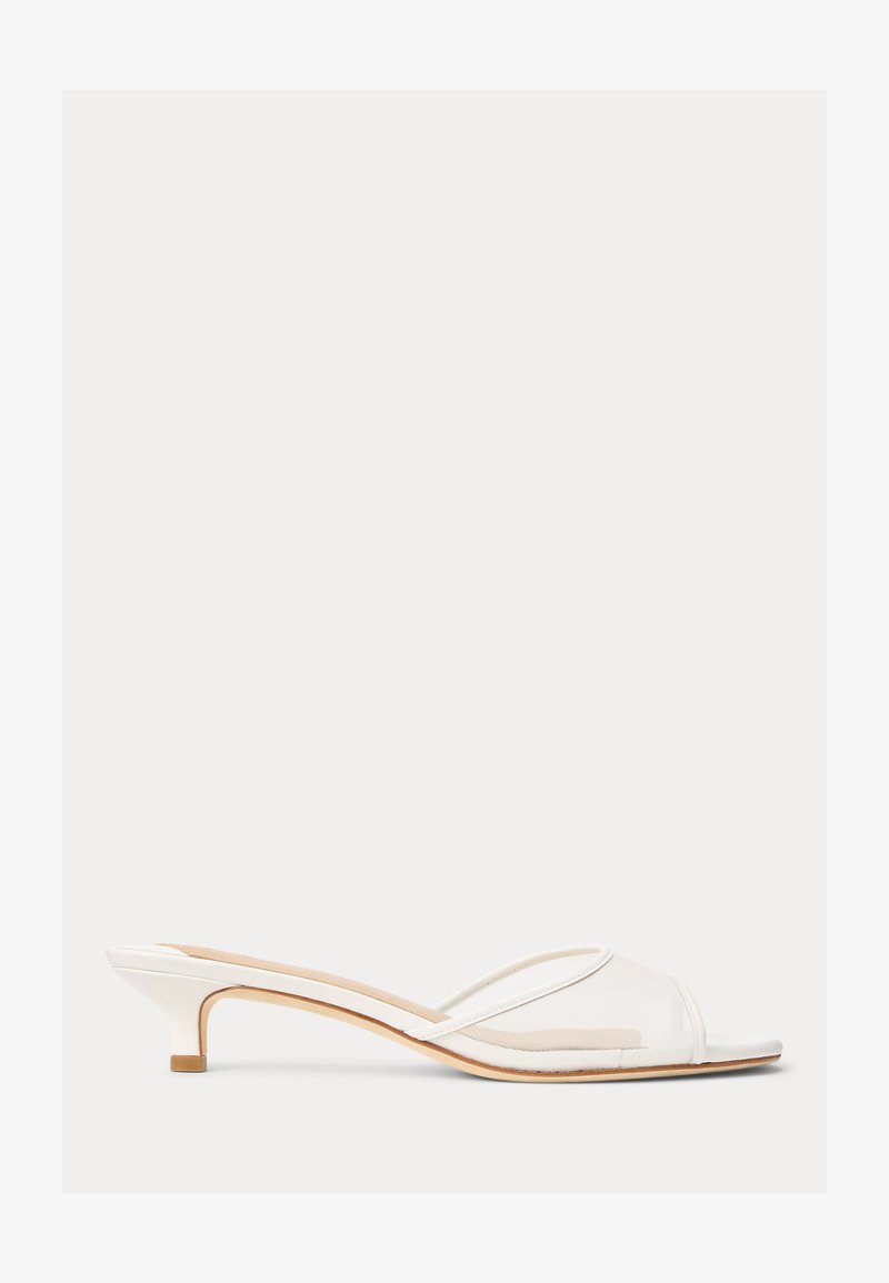 Hvit lavhællet mule-sandal med gjennomsiktig meshlokk og tynn stropp over tærne, beige innersåle og slank stablet hæl.