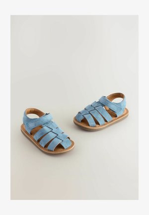 Sandale din suede de culoare albastru deschis, cu un design împletit, vârful deschis, curea reglabilă și talpă din cauciuc bej. Ideale pentru vreme caldă.