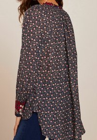 Mønsteret bluse i marineblå med små blomstermotiver, med en samlet halsudskæring og broderede manchetter. Let og flydende stof.