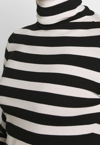 Maglione a collo alto a righe nere e crema, con un design aderente caratterizzato da strisce larghe e strette alternate in una morbida trama lavorata a maglia.