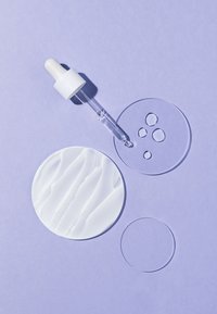 Compteur en verre clair avec un bulbe blanc au-dessus de disques circulaires blancs et transparents sur un fond violet. Les disques présentent des surfaces texturées et lisses.
