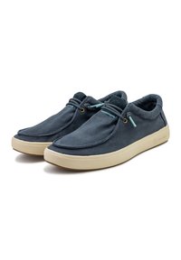 Slip-on čevlji z zgornjim delom iz temno modrega platna, okroglo konico in svetlo bež gumo; imajo nastavljive vezalke in minimalne šiviljske detajle.