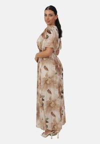 Robe maxi à manches courtes en tissu beige clair avec un motif floral crème et vert. Taille élastique ; silhouette fluide.