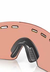 Occhiali da sole con lenti rosa curve e montatura nera, para naso esagonale texturizzato e fessure di ventilazione lungo la parte superiore per il passaggio dell'aria.