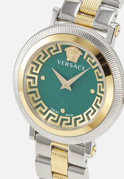 Versace watch with a gold and silver metallic bracelet. Round green textured dial features gold Greek key pattern and a Medusa emblem.