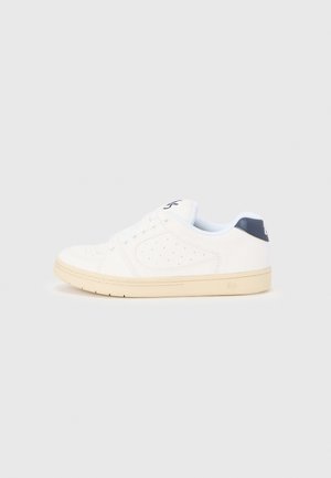 Zapatilla blanca con parte superior texturizada, puntera redonda y detalles perforados. Cuenta con una lengüeta en el talón azul oscuro a contraste y suela de goma.