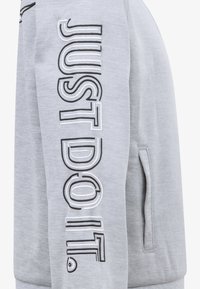 Sweatshirt gri caracterizat prin textul "JUST DO IT." într-un design îndrăzneț alb și negru, cu un buzunar lateral și un material moale la atingere.