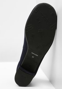 Svart gummisula med präglat skopattern, övre del i mörkblått tyg, med rund tå och låg klack. Storlek 37, märkt "TILLVERKAD I SPANIEN."