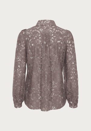Spetsblus i mauve med blommönster, lång �ärm och krage. Bakdelen har knäppning och en något lös passform.
