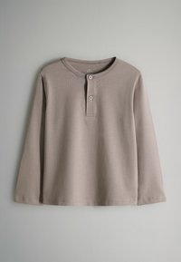 Majica dugih rukava s okruglim izrezom u svijetloj taupe boji, napravljena od mekog pamuka, sa tri gumba na ovratniku i ravnim rubom.