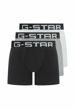 Drie paren G-Star boxershorts: zwart, grijs en wit. Elk heeft een zwarte merkband met witte letters en een strakke pasvorm.