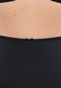 Zwarte stoffen ondergoed met een gladde textuur, een lage taille en een klein zwart strikje accent in het midden van de achterkant.