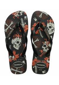 Havaianas con tiras texturizadas negras. El diseño presenta calaveras, flores y huesos en rojo y blanco sobre un fondo negro.