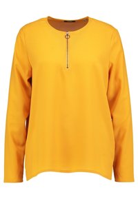 Žlutý top s dlouhým rukávem, vyrobený z měkké tkaniny. Má kulatý výstřih a přední zip s kruhovým vytahovákem. Rovný lem.
