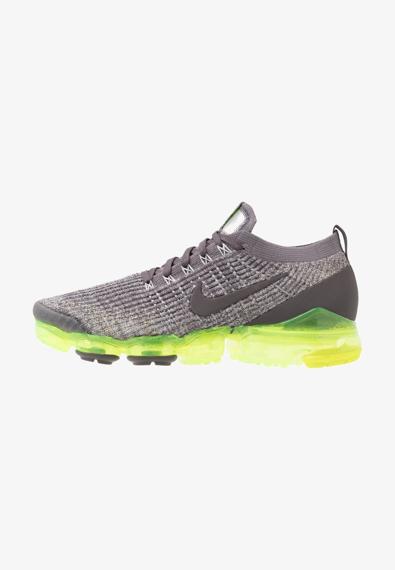 Tenisky Nike Air VaporMax s šedým pleteným svrškem, černým logem swoosh a jasně zelenou průhlednou podrážkou. Lehký, prodyšný design.