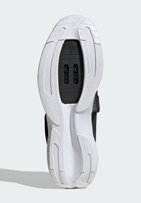 Semelle de chaussure de sport noire avec une semelle extérieure en caoutchouc blanc texturé. Présente deux trous noirs pour la ventilation et un design de talon lisse.