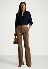 Ναυτικά μπλουζάκι με V λαιμόκοψη, καφέ παντελόνι καμπάνα από βελουτέ, καφέ ζώνη και μικρή τσάντα με δερμάτινους λεπτομέρειες. Τα τακούνια ολοκληρώνουν την εμφάνιση.