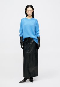 Ανοιχτό μπλε πλεχτό πουλόβερ, μαύρη δερμάτινη μάξι φούστα, μαύρα γάντια και μυτερά μαύρα ψηλοτάκουνα παπούτσια; απλός σχεδιασμός, αντιθετικά χρώματα και κομψές υφές.