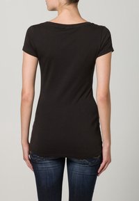 Svart kortärmad t-shirt med rund halsringning, tillverkad av mjuk bomull. Har en något längre bakre fåll och en figurnära silhuett.