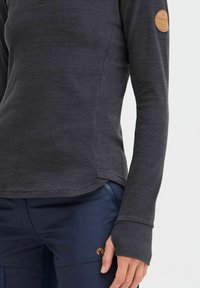 Long-sleeve, dark gray top made from textured fabric, featuring a round neckline, side seam details, and a brown logo patch on the sleeve.