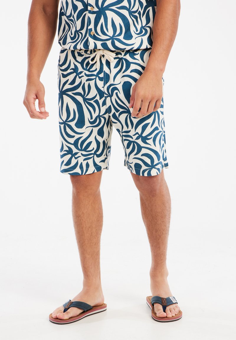 Katoenmengsel shorts met een witte achtergrond en een donkerblauw abstract bladerenpatroon. Voorzien van een verstelbare taille met een trekkoord.