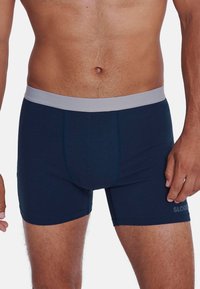 Boxer shorts blu navy realizzati in un tessuto morbido, con una cintura elastica grigia chiara e una discreta marca sul lato.